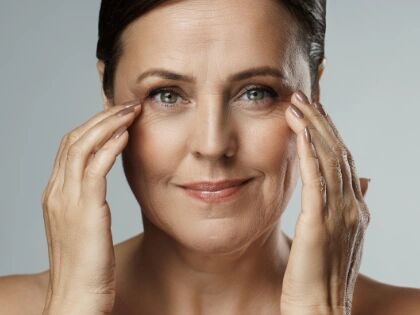 A woman touching the skin under her eyes with her fingertips